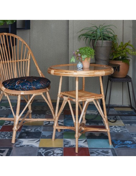 Table en osier Honorine verre diam. 50 en ambiance avec le fauteuil Marius