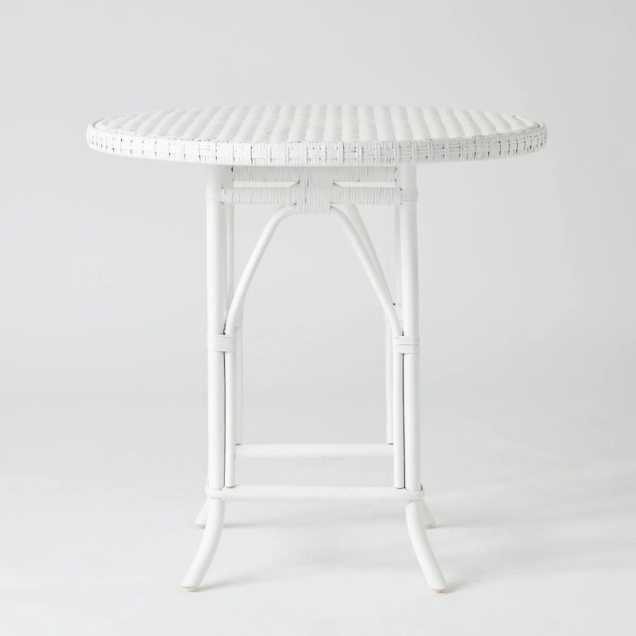 Front view of round table with white lacquered rattan woven top from the Primavera collection