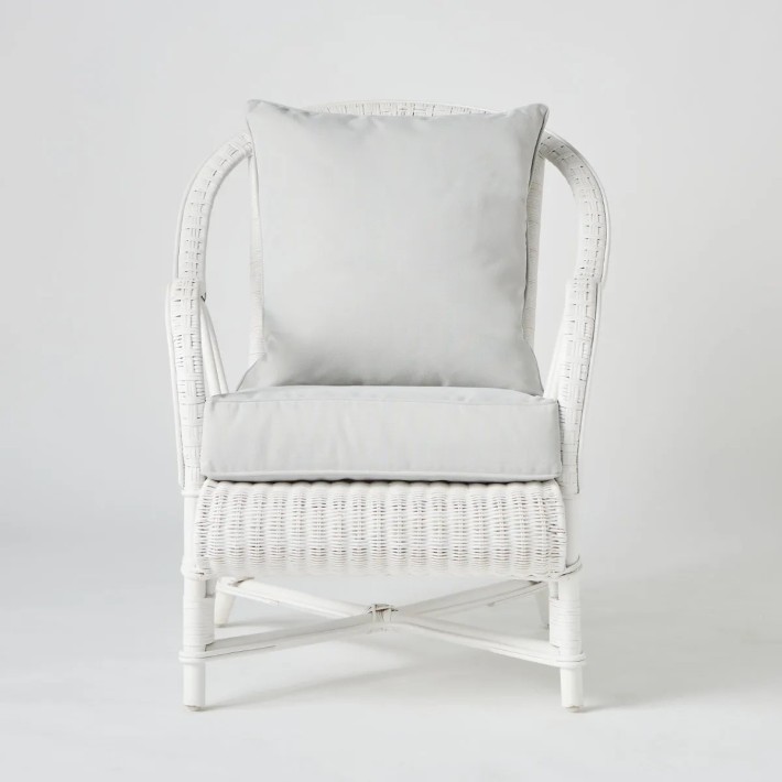 Front view of white lacquered woven rattan armchair with PRIMAVERA cushions
