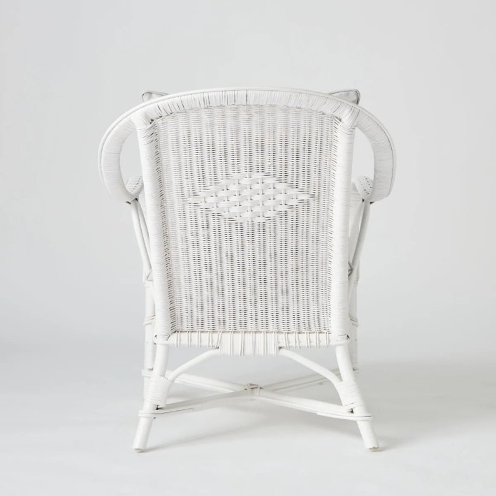 Rear view of white lacquered rattan armchair with grey cushions from the PRIMAVERA collection