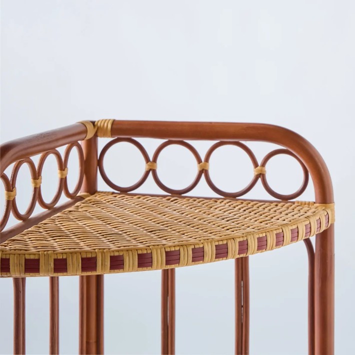Close-up of a woven rattan tray with red resin edging from the BAGATELLE collection